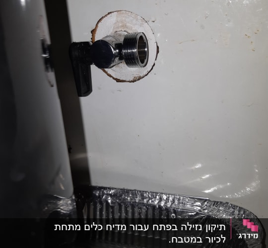 ברז מתכת מותקן בקיר עם מגש מתחתיו
